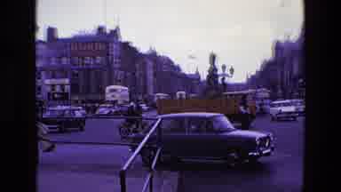Ireland (1969): Pedestrian Driving Motorcycle In Busy Traffic Stops Near Officer