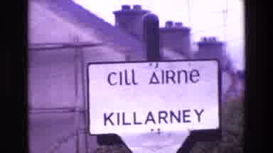Ireland (1969): Killarney Signpost With Chimneys In Background And City With