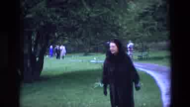 Ireland (1969): Woman Dressed In Dark Fur Coat Looking At A Flower In A Park With