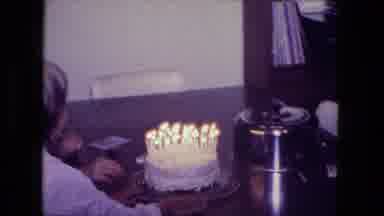 Fort Wayne Indiana (1974): Person Slides Birthday Cake With Lit Candles On It In