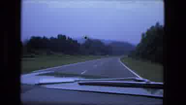 Fort Wayne Indiana (1974): A Car Running On The Highway Going Through Forest Land