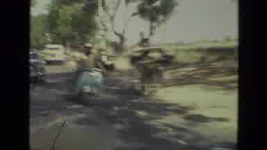 India (1974): Moto Driving Fast Through Busy Street