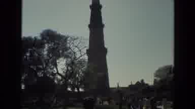 India (1974): People Walking Past Stone Tower On A Bright Sunny Day