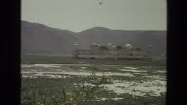 India (1974): Amidst A Barren Field A Large Building Is Seen In The Distance With