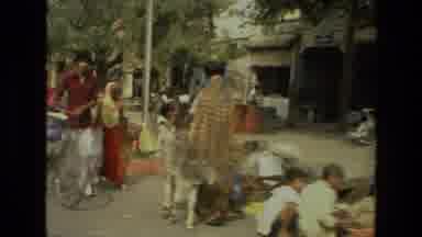 India (1974): People And Street Life In India With People Riding Bikes Through A