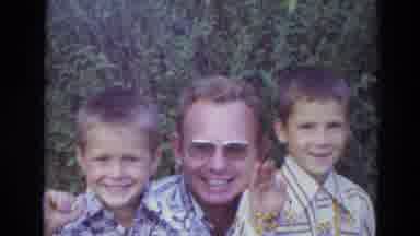 Lincoln Nebraska (1974): Man Wearing Sunglasses Instructing Two Boy Kids To Wave