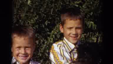 Lincoln Nebraska (1974): Two Young Boys Hold A Black Dog And Wave To The Camera