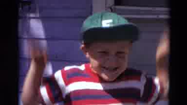 Lincoln Nebraska (1974): Little Boy Wearing Green Baseball Cap Acts Goofy Waving