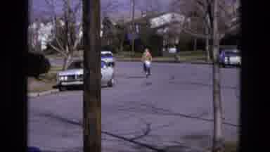 California USA (1975): Person Pedals Bicycle Along Street Next To White Parked Car