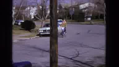 California USA (1975): Person Cycling Down The Street In A Suburban Area