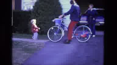 CALIFORNIA USA-1975: Adult On Bicycle With Blue Basket And Child In Suburban Neighborhood