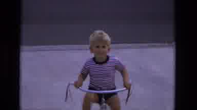 California USA (1975): A Kid Playing And Cycling Around The House On A Pathway