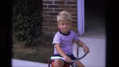 California USA (1975): A Young Boy Rides A Tricycle And Also Sits In The Backseat