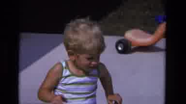 California USA (1975): Boy Trying To Ride A Tricycle In Backyard