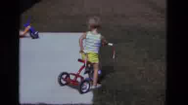 California USA (1975): Young Kid In Striped Tank And Yellow Bottoms Trying To Ride