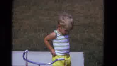 California USA (1975): Child In The Summer Wearing Shorts Next To A Bicycle