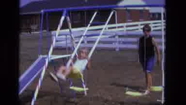 California USA (1975): The Mom Is Outside Pushing Her Son On The Swing