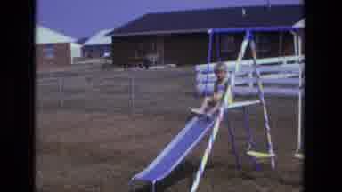 California USA (1975): A Child Sits Atop A Sliding Board And Begins To Descend