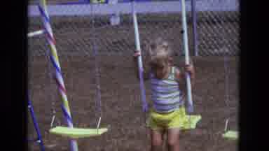 California USA (1975): Child Sitting On Swings On Play Structure Looking Down At