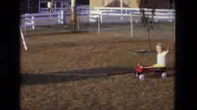 California USA (1975): Atv Pulls Wagon With Child Riding In It Across Yard With
