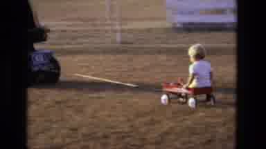 California USA (1975): Small Child In A Wagon Being Pulled Along By A Lawn Tractor