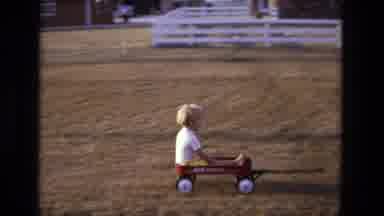 California USA (1975): Little Boy Is Towed Along In A Red Cart By His Dad On A