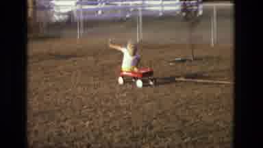 California USA (1975): Man On A Riding Lawn Mower Pulling A Boy In A Wagon Behind
