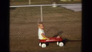 California USA (1975): Kid Having A Great Time Riding In His Little Red Wagon
