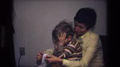 California USA (1975): Woman Has Little Boy Sitting On Her Knee While She Puts His