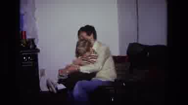 California USA (1975): Father Putting Shoe On Child And Teaching Them How To Tie