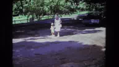 California USA (1975): Old Woman Walks A Child On A Path Alongside A Field