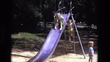 California USA (1975): Two Small Children Taking Turns Climbing Up And Sliding