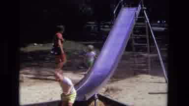 California USA (1975): Young Children Playing In A Park Using A Metal Slide And