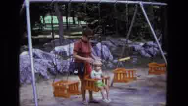California USA (1975): An Adult Pushing Child On Swing At The Park