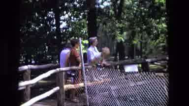 California USA (1975): People Are Standing With A Child Along A Wooden Fence