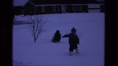 California USA (1975): 2 Children Playing In The Snow While A Person Across The