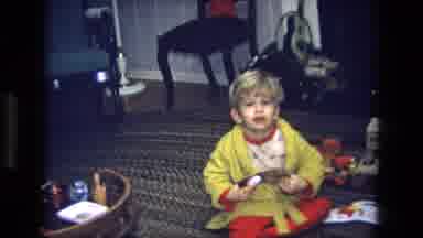 California USA (1975): Little Boy Wearing Pajamas And A Yellow Rob Holds Up A Car