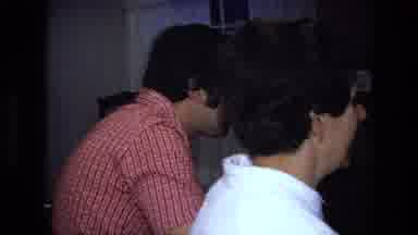 California USA (1975): 2 Adult Men Watching Young Boy Opening Gifts