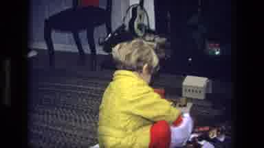 California USA (1975): Boy Wearing Yellow Robe Removes Object From White Christmas