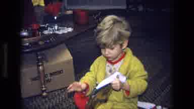 California USA (1975): A Child In A Yellow Robe And Red Pajamas Opening A