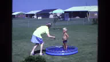 California USA (1975): Boy In Swimsuit Standing In Shallow Blow Up Child Pool And