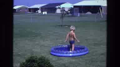 California USA (1975): Young Boy Wading In Backyard Kids Pool