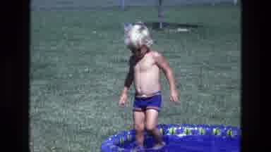 California USA (1975): Young Blonde Boy In Blue Shorts Plays In A Tiny Blue Pool