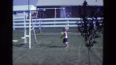 California USA (1975): Little Boy Runs Across The Garden With A Yellow Balloon In