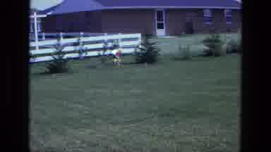 California USA (1975): Little Kid Picking Up Toy And Running In The Yard