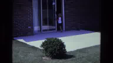 California USA (1975): Little Boy Using A Sliding Door To Get Inside The House