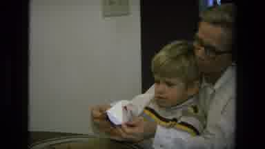 California USA (1975): Child Performing Paper Crafts With Adult Supervision