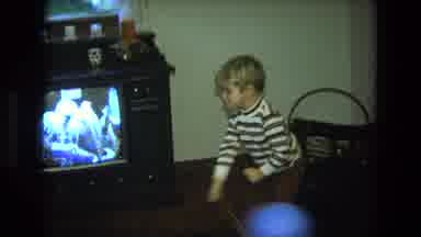 California USA (1975): Young Boy Sits On A Chair In A Living Room Playing With A