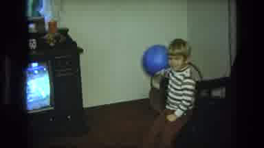 California USA (1975): A Young Boy Playing With A Blue Balloon Next To A Tv