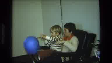 California USA (1975): Young Boy Sitting On A Woman's Lap As He Happily Holds A